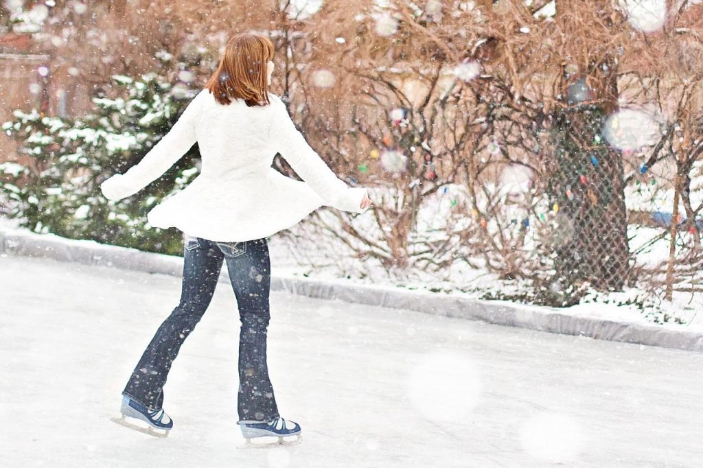 Bezoekers schaatsen op de ijsbaan in Roermond met winterdecoratie en verlichte sfeer in de achtergrond